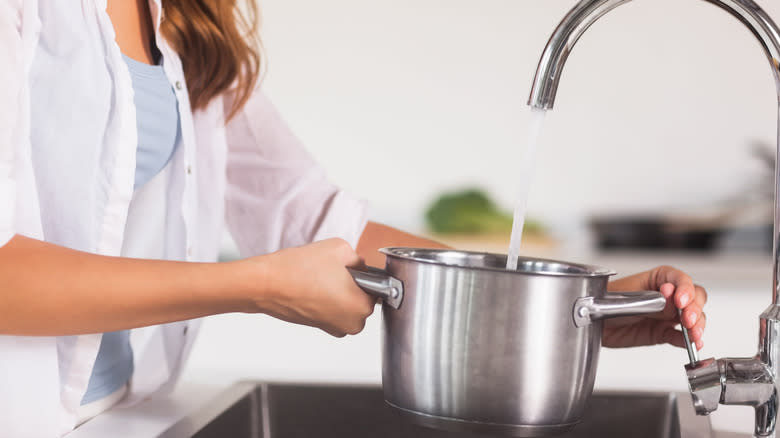 Woman filling pot, cold water