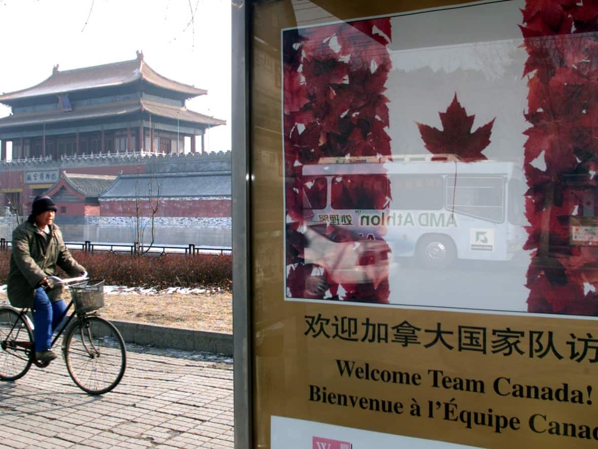 A Chinese man cycles past a billboard in front of Beijing's Forbidden City before a 2001 visit by then-Canadian prime minister Jean Chretien. At the time, concerned U.S. officials were secretly probing Chinese operations in Canada. (Reuters - image credit)