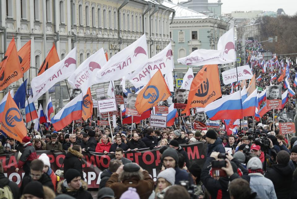 Demonstrators, with flags of different opposition movements, march in memory of opposition leader Boris Nemtsov in Moscow, Russia, Sunday, Feb. 24, 2019. Thousands of Russians took to the streets of downtown Moscow to mark four years since Nemtsov was gunned down outside the Kremlin. (AP Photo/Pavel Golovkin)