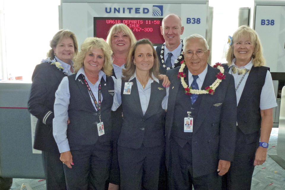 In this Aug. 25, 2012 photo provided by his family, Ron Akana, second from rigtht, wears a red and white lei while surrounded by his crewmates, including daughter Jean Akana-Lewis, center, at Denver International Airport before Akana's final working flight of his 63-year career. Akana is being honored by Guinness World Records as record-holder for the longest-serving flight attendant. (AP Photo/Courtesy of Jean Akana-Lewis)