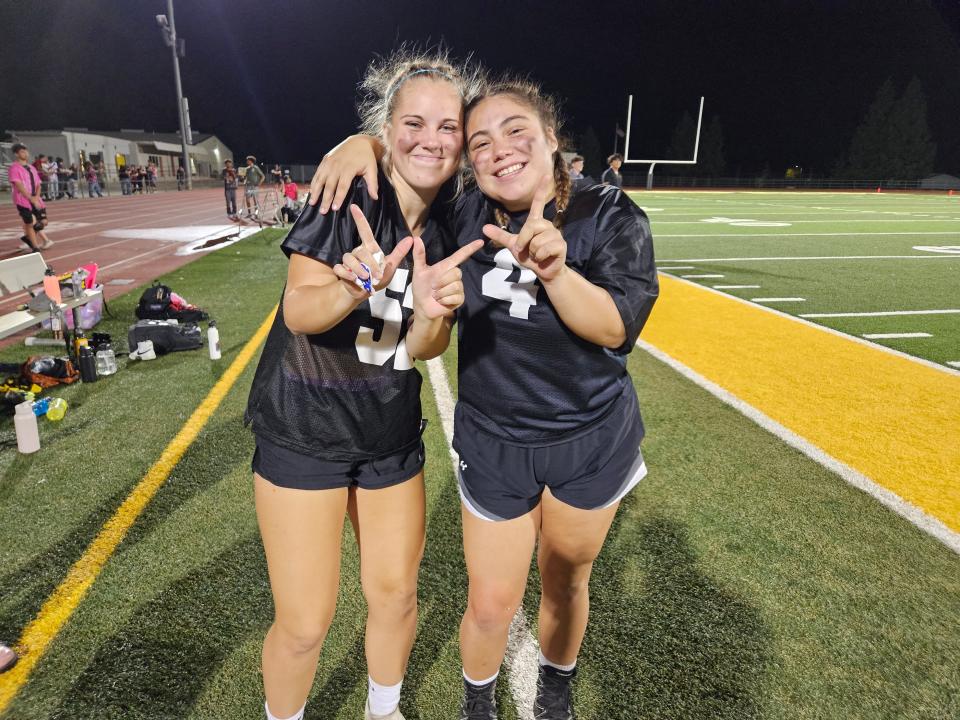 Enterprise seniors Ashley Wellman (left) and Alianna Beltran (right) throw up win signs after guiding the seniors over the juniors during the school's powderpuff football game on Wednesday, Sept. 13, 2023.