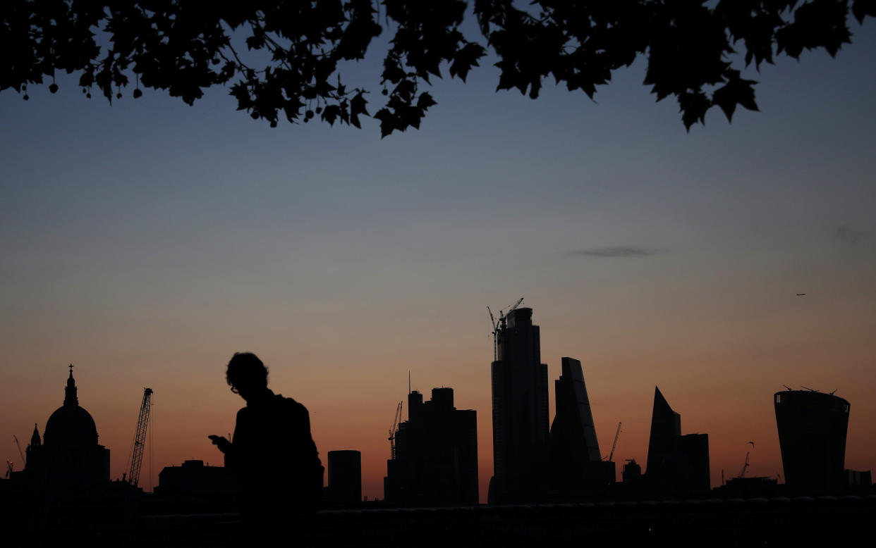 A man walks past the city of London financial district as dawn breaks in London, Britain August 20, 2019. REUTERS/Hannah McKay