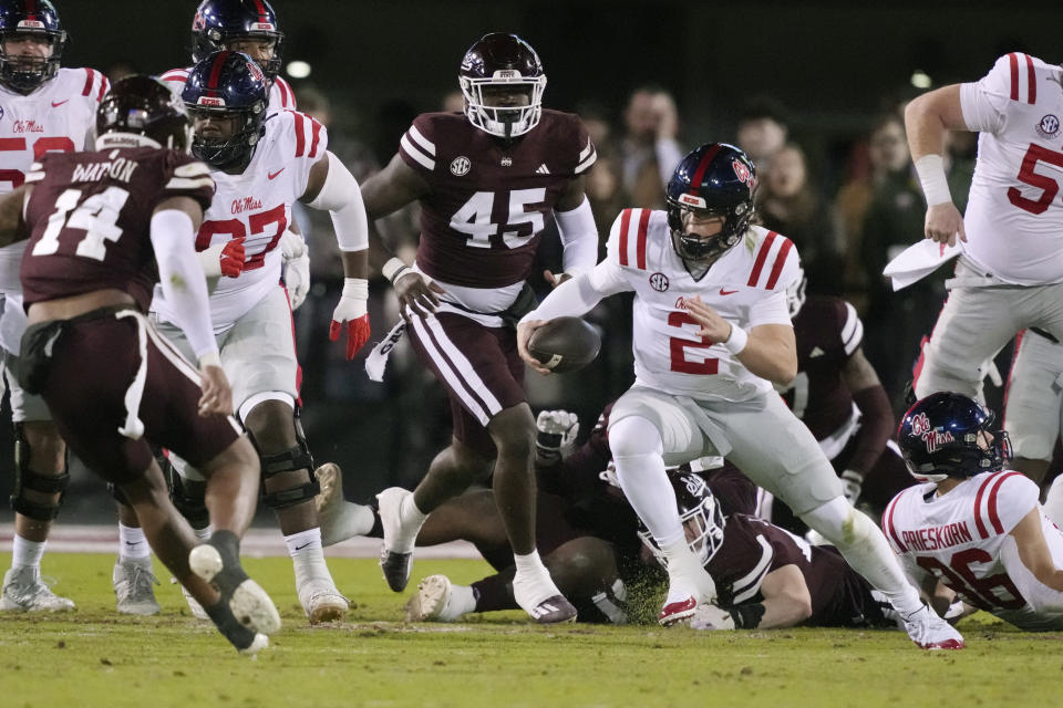 Mississippi quarterback Jaxson Dart (2) dodges Mississippi State defenders as he runs for a short gain during the first half of an NCAA college football game in Starkville, Miss., Thursday, Nov. 23, 2023. (AP Photo/Rogelio V. Solis)