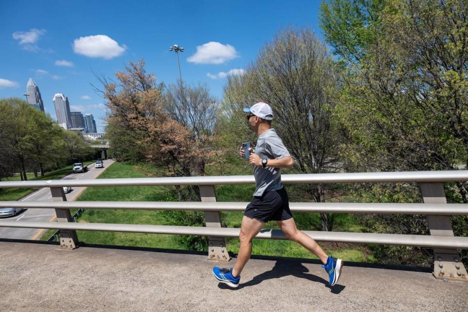 Théoden Janes runs on the sidewalk along the part of Central Avenue that crosses over I-277, as the uptown skyline looms in the background.