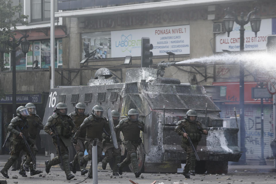 Riot police charge anti-government demonstrators during clashes in Santiago, Chile, Tuesday, Oct. 29, 2019. Chileans gathered Tuesday for a 12th day of demonstrations that began with youth protests over a subway fare hike and have become a national movement demanding greater socio-economic equality and better public services in a country long seen as an economic success story. (AP Photo/Rodrigo Abd)