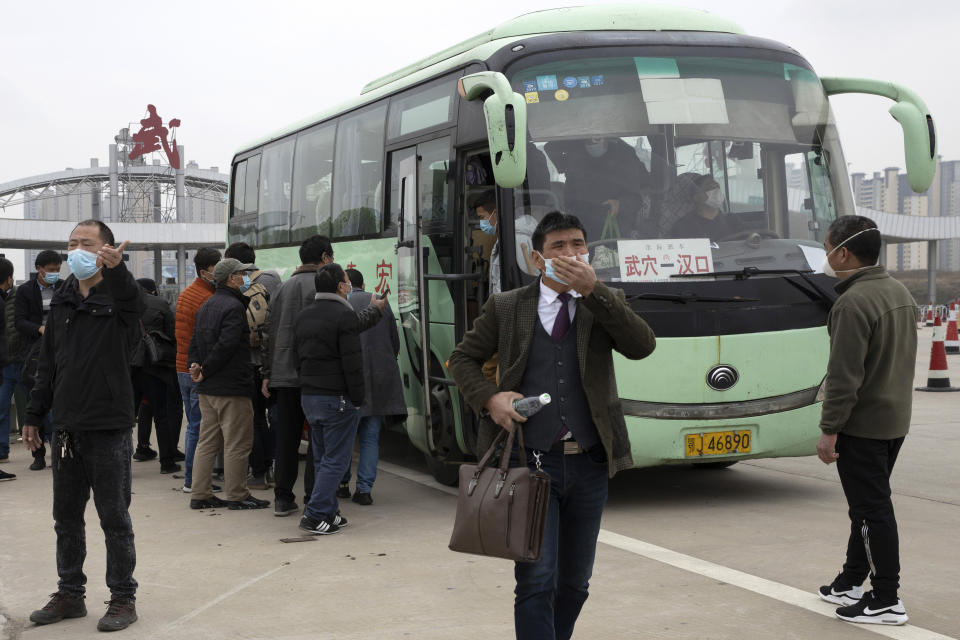 Personas descienden de un autobús el jueves 2 de abril de 2020 a su llegada a la ciudad de Wuhan, que continúa aislada debido al brote de coronavirus, en la provincia de Hubei, en el centro de China, pero que ha comenzado a permitir el regreso de algunos habitantes. (AP Foto/Ng Han Guan)