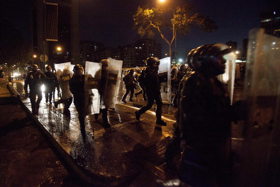 Bolivarian National Guard Officers run to stop a protest in Plaza Altamira, Caracas, Venezuela, Friday, March 14, 2014. The Venezuelan government is stepping up security operations in Caracas and other cities where demonstrators are blocking streets, avenues and highways. President Nicolas Maduro said that those involved in creating road barricades will be arrested. (AP Photo/Alejandro Cegarra)