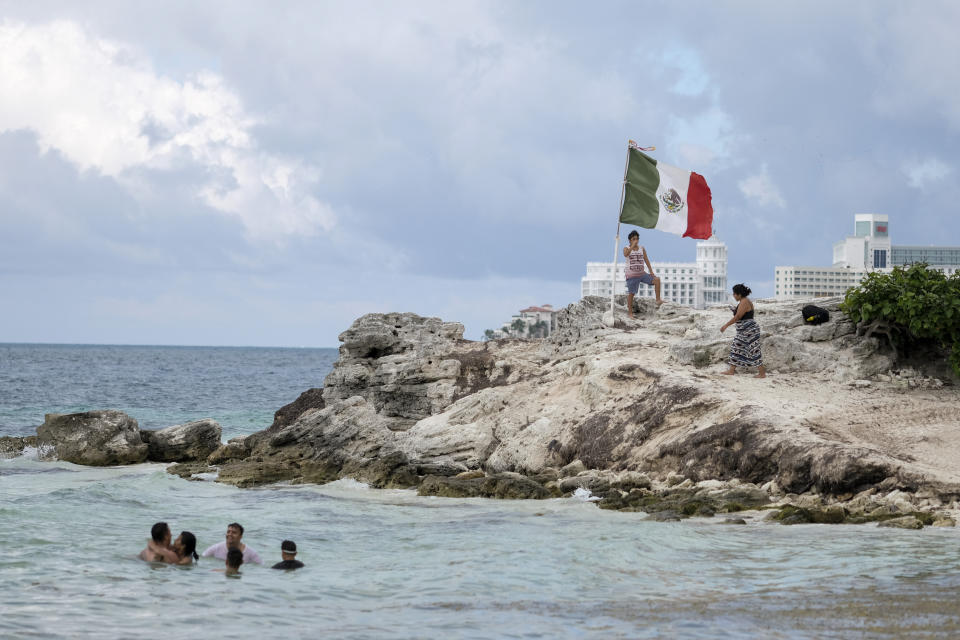 People spend time on the coast of Cancun, Mexico, Saturday, June 13, 2020. An irony of the coronavirus pandemic is that the idyllic beach vacation in Mexico in the brochures really does exist now: the white sand beaches are sparkling clean and empty on the Caribbean coast. (AP Photo/Victor Ruiz)