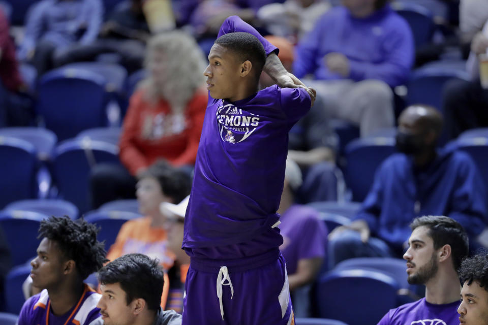 Hansel Enmanuel, a freshman guard from the Dominican Republic for Northwestern State, stretches at the bench before entering an NCAA college basketball game against Rice Saturday, Dec. 17, 2022, in Houston. Enmanuel lost his left arm in a childhood accident and has attained the talent and skill to play at the college level. (AP Photo/Michael Wyke)