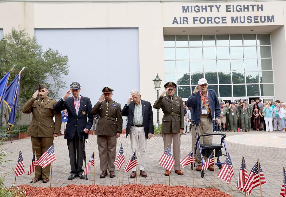 WWII Veterans Maj. John "Lucky" Luckadoo, TSgt. Gordon Fenwick and LT. John Rasmussen are joined by costumed reenactors as they salute after placing the final flags,on Friday. May 26, 2023 during the Flags for the Fallen opening ceremony at the National Museum of the Mighty 8th Air Force in Pooler, Georgia.