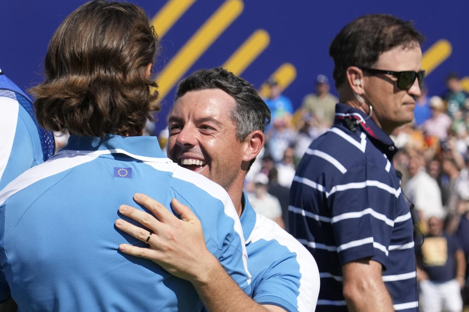 Europe's Rory Mcilroy, center, celebrates with playing partner Europe's Tommy Fleetwood after they won their morning Foursome match 2&1, in the background is United States' Team Captain Zach Johnson, at the Ryder Cup golf tournament at the Marco Simone Golf Club in Guidonia Montecelio, Italy, Friday, Sept. 29, 2023. (AP Photo/Andrew Medichini)