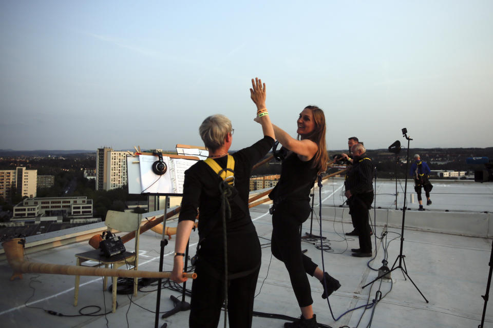 Musicians with alp horns celebrate after they perform on the roof of an apartment block for a concert featuring distant harmonies, at a time when cultural events have been disrupted by the coronavirus pandemic, in the Prohlis neighborhood in Dresden, Germany, Saturday, Sept. 12, 2020. About 33 musicians of the Dresden Sinfoniker perform a concert named the 'Himmel ueber Prohils', The Sky above Prohlis, on the roof-tops of communist-era apartment blocs in the Dresden neighborhood Prohlis. (AP Photo/Markus Schreiber)