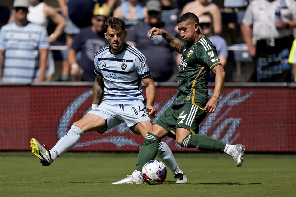 Portland Timbers midfielder Marvin Loría, right, kicks the ball under pressure from Sporting Kansas City defender Tim Leibold (14) during the second half of an MLS soccer match Sunday, May 28, 2023, in Kansas City, Kan. Sporting Kansas City won 4-1. (AP Photo/Charlie Riedel)