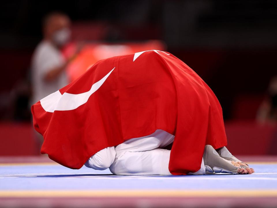 Hatice Kubra İlgun of Team Turkey curls up under the Turkish flag after competing in taekwondo.