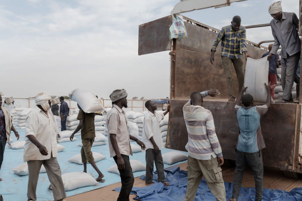 People unload food from WFP trucks during the monthly distribution at Adrè.<span class="copyright">Nicolò Filippo Rosso</span>