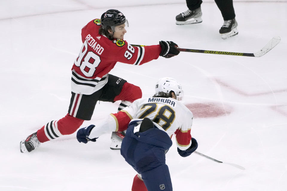 Chicago Blackhawks' Connor Bedard follows through on his goal as Florida Panthers' Josh Mahura defends during the second period of an NHL hockey game Saturday, Nov. 4, 2023, in Chicago. (AP Photo/Charles Rex Arbogast)