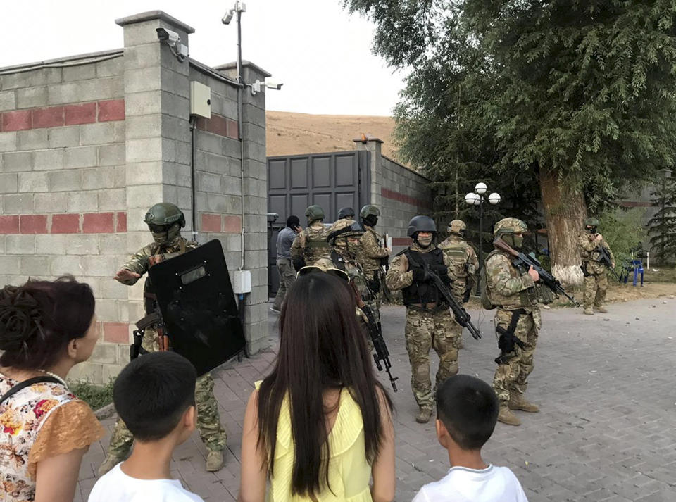 Kyrgyz special forces stand in guard at former president of Kyrgyzstan Almazbek Atambayev's residence in the village of Koi-Tash, about 20 kilometers (12 miles) south of the capital, Bishkek, Kyrgyzstan, Wednesday, Aug. 7, 2019. Gunfire is being heard outside the residence of the former president of Kyrgyzstan as police move in to try to arrest him. The Kyrgyz news site 24.kg said several people, including journalists, have been wounded in the Wednesday shooting in the village of Koi-Tash, 20 kilometers (12 miles) south of the capital, Bishkek. (AKIpress via AP)