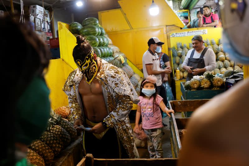 Lucha libre fighters encourage maskless Mexicans to wear masks at the Central Abastos market, in Mexico City