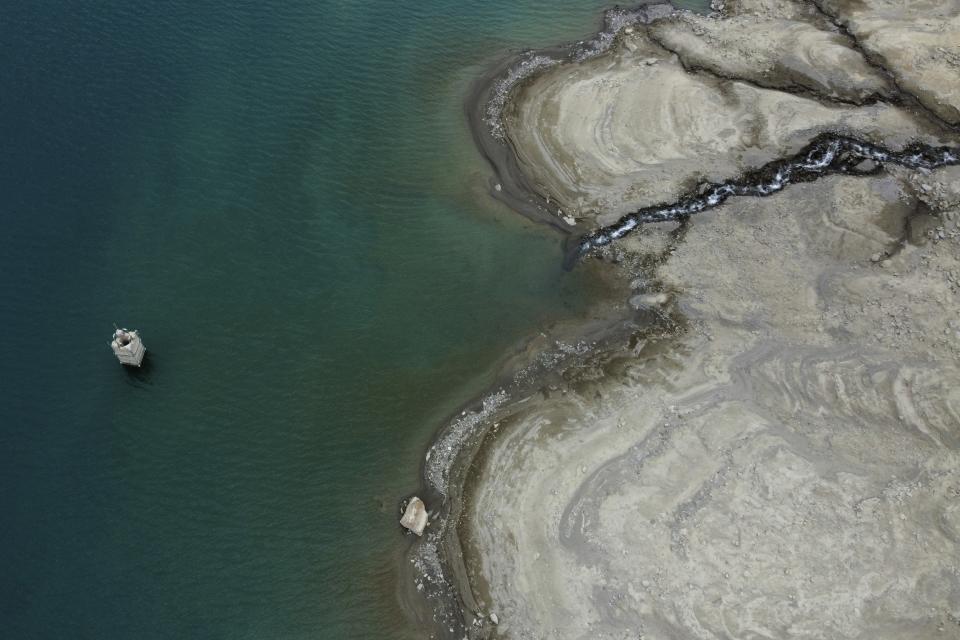 A dry cracked bed surrounds the artificial Vernago lake, in Vernago, near the Val Senales glacier, northern Italy, Monday, April 17, 2023. The lakes are so parched an old tower is resurfacing from the bed. (AP Photo/Luca Bruno)