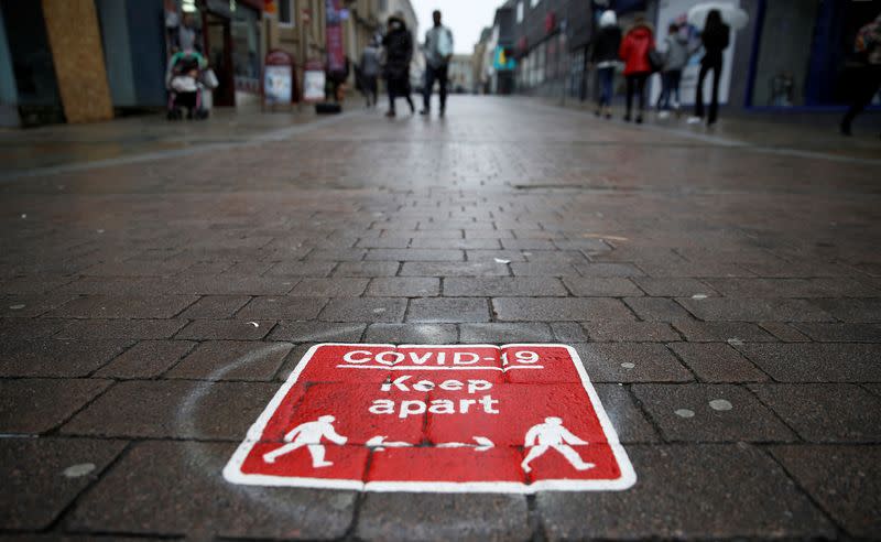 People walk past a social distancing marker following the outbreak of the coronavirus disease (COVID-19) in Bolton, Britain