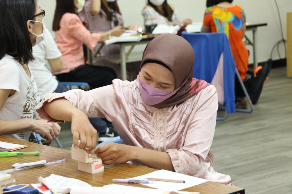 《圖說》家住蘆洲的印尼籍新住民陳優妮，認真學習如何利用牙線做幼兒口腔清潔。〈社會局提供〉