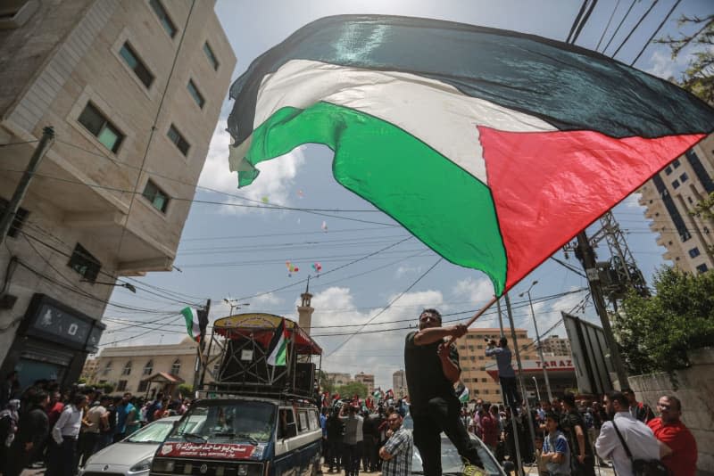 A man waves the Palestinian national flag during during a rally marking the 74th anniversary of Nakba Day (Memory of the Catastrophe). Palestinians are set to commemorate the loss of their homeland on Wednesday by observing Nakba Day (Catastrophe Day) which marks the flight of more than 700,000 Palestinians during the 1948 war that led to the establishment of the state of Israel. Mohammed Talatene/dpa