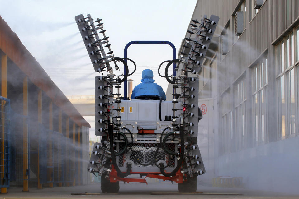 A worker in a tractor operates electrostatic spraying to disinfect the workplace following the coronavirus outbreak, in Yantai city in east China's Shandong province, Sunday, Feb. 9, 2020. China's virus death toll rose above 800, passing the number of fatalities in the 2002-2003 SARS epidemic, but fewer new cases were reported in a possible sign its spread may be slowing as other nations step up efforts to block the disease. (Chinatopix via AP)