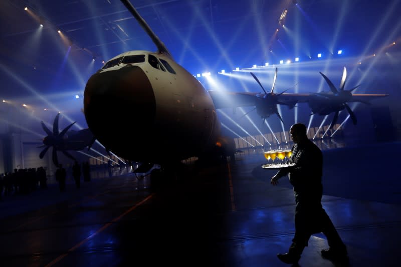 A waiter walks past an Airbus A400M military transport plane is parked at the Airbus assembly plant during an event in the Andalusian capital of Seville, southern Spain, December 1, 2016. REUTERS/Marcelo del Pozo