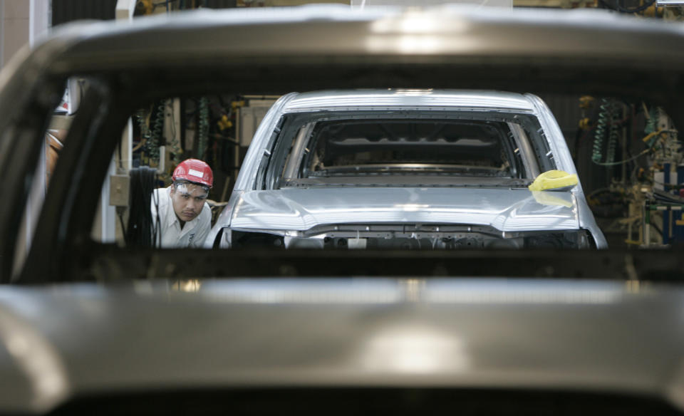 Trabajadores de la línea de montaje revisan las carrocerías de una fila de camionetas Toyota Tacoma que bajan por la línea de montaje en Toyota Motor Manufacturing de Baja California. 13 de diciembre de 2004 (Archivo. Foto de Mark Boster/Los Angeles Times vía Getty Images)