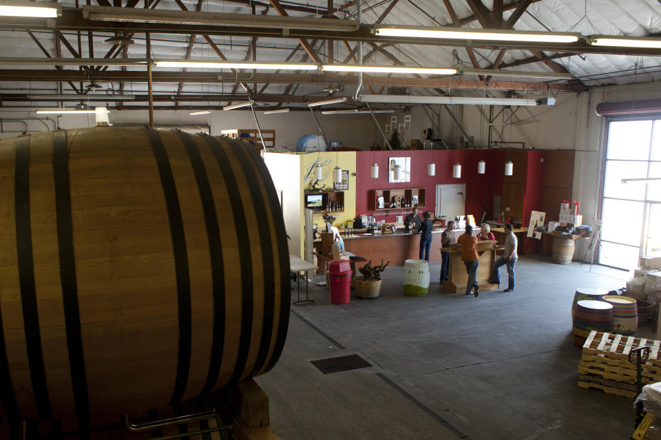 In this photo taken Thursday July 12, 2012, people enjoy the wine tasting room at Dashe Cellars in Oakland, Calif. Growing up in the shadow of an icon is never a shoe-in, whether you’re a wannabe princess related to that attention-grabbing vamp Cinderella or a city living next door to fabled San Francisco. The winery is a producer of some standout zinfandels. (AP Photo/Eric Risberg)