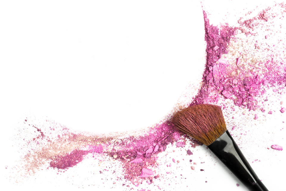 A cosmetic brush with a sweep of rose-pink powder