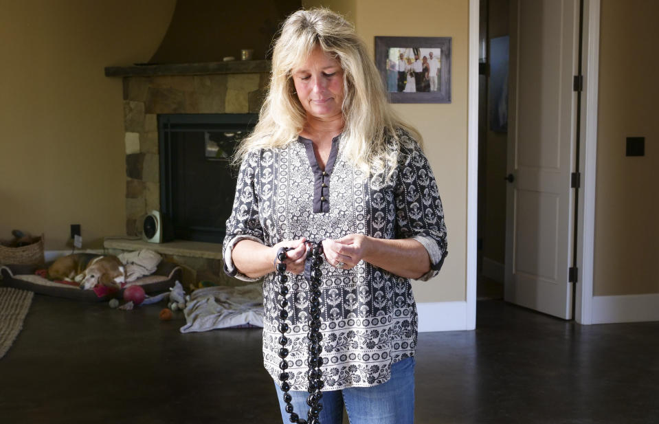 In this Monday, Nov. 4, 2019, photo, Tina Chandler looks through her Kukui Nut Lei, as she recalls packing them with a family portrait when she evacuated with during the Kincade Fire, in the Fountaingrove neighborhood of Santa Rosa, Calif. Two years ago, the Chandlers had only minutes to escape before their longtime family home burned to the ground before their eyes. They rose from the ashes to build a new home. The night of the fire Chandler packed a framed family photo along with a box of kukui nut necklaces that a friend had sent from Hawaii after they lost their home. "I know that sounds kind of silly," she said of the black shiny nuts, which represent hope and renewal. "But this was their way of saying 'We're going to be alright." (AP Photo/Lacy Atkins)