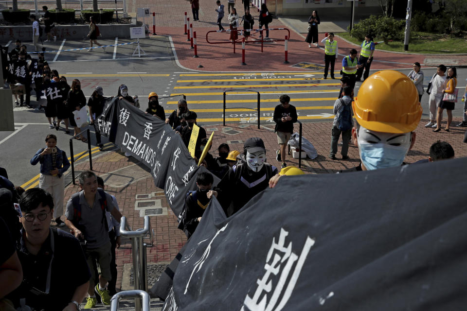 University students wearing Guy Fawkes masks, hold banner as they march to their graduation ceremony at the Chinese University of Hong Kong, in Hong Kong, Thursday, Nov. 7, 2019. The banner reads " Five demands, not one less." (AP Photo/Kin Cheung)