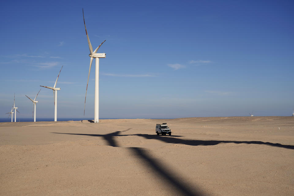 FILE - A vehicle drives near wind turbines at Lekela wind power station, near the Red Sea city of Ras Ghareb, some 300 km (186 miles), from Cairo, Egypt, Oct. 12, 2022. The U.N. climate summit is back in Africa after six years and four consecutive Europe-based conferences. The conference — known as COP27 — will be held in the resort city of Sharm el-Sheikh in Egypt. (AP Photo/Amr Nabil, File)