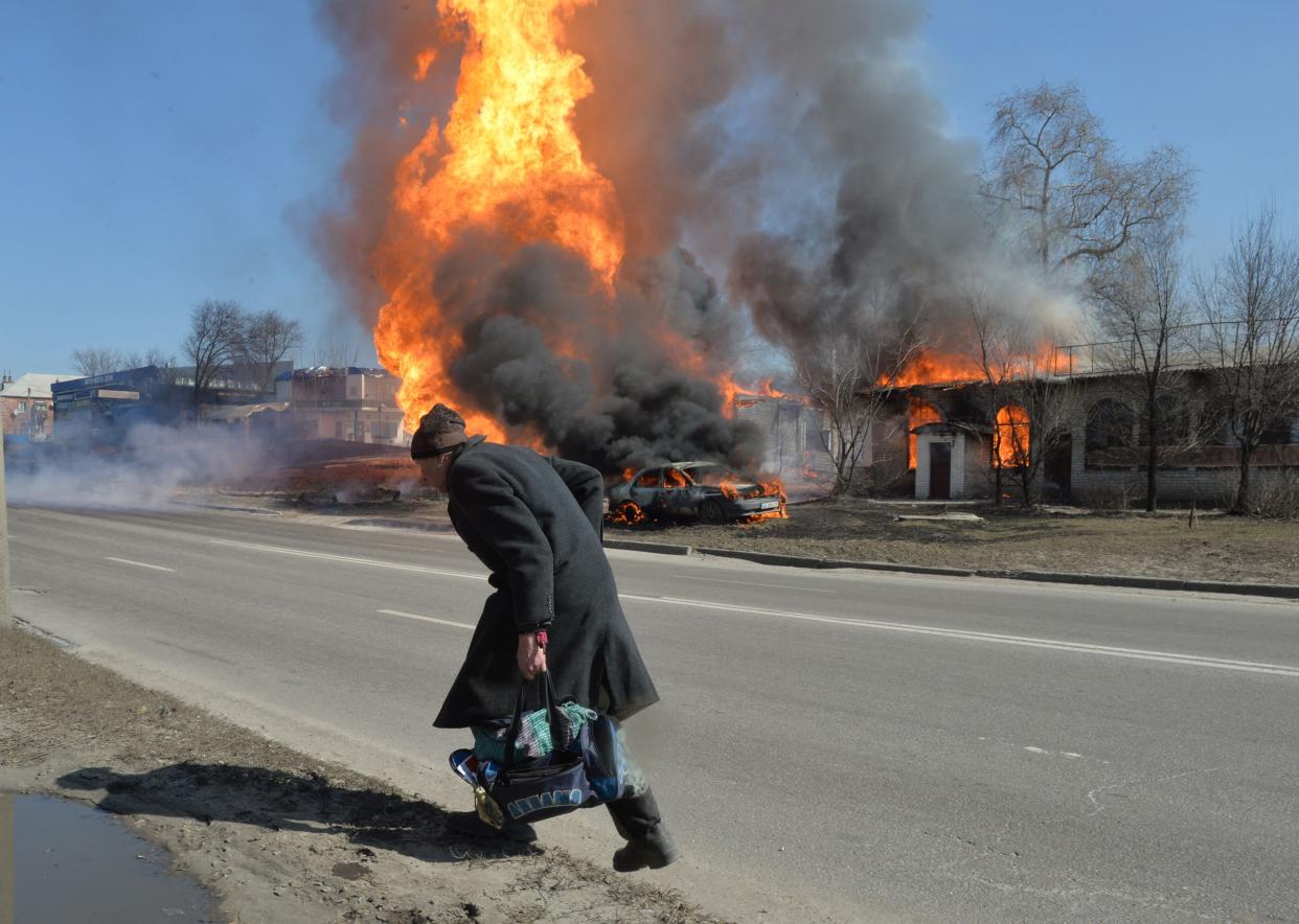 An elderly man walks as fire engulfs a gas station following an artillery attack on of Kharkiv, Ukraine.