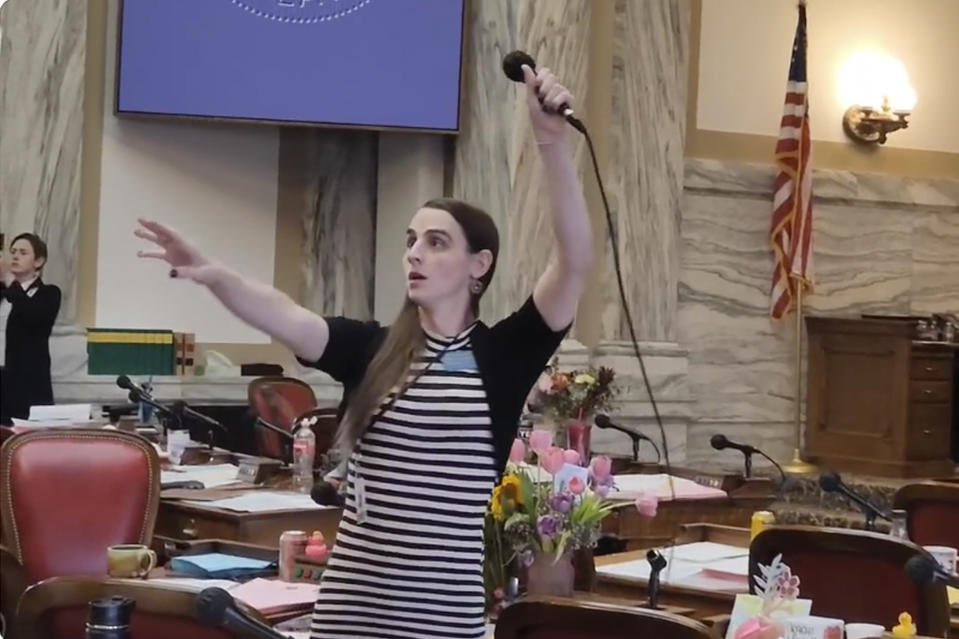 FILE - Montana Democratic Rep. Zooey Zephyr hoists a microphone into the air on Monday, April 24, 2023, as her supporters interrupt proceedings in the state House by chanting "Let Her Speak!" in Helena, Mont. The silencing of Zephyr, a transgender lawmaker in Montana, marks the third time in a month that Republicans have attempted to compare disruptive but otherwise peaceful protests at state capitols to insurrections. The tactic follows a pattern set over the past two years when the term has been misused to describe public demonstrations and even the 2020 election that put Democrat Joe Biden in the White House. (AP Photo/Amy Beth Hanson, File)