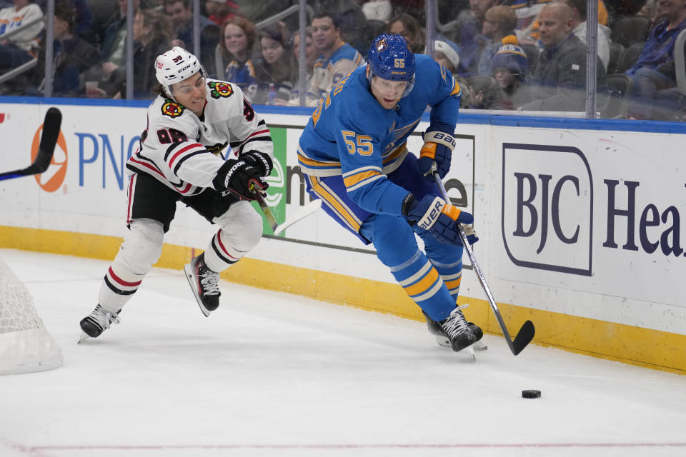 St. Louis Blues' Colton Parayko (55) and Chicago Blackhawks' Connor Bedard chase after a loose puck along the boards during the first period of an NHL hockey game Saturday, Dec. 23, 2023, in St. Louis. (AP Photo/Jeff Roberson)