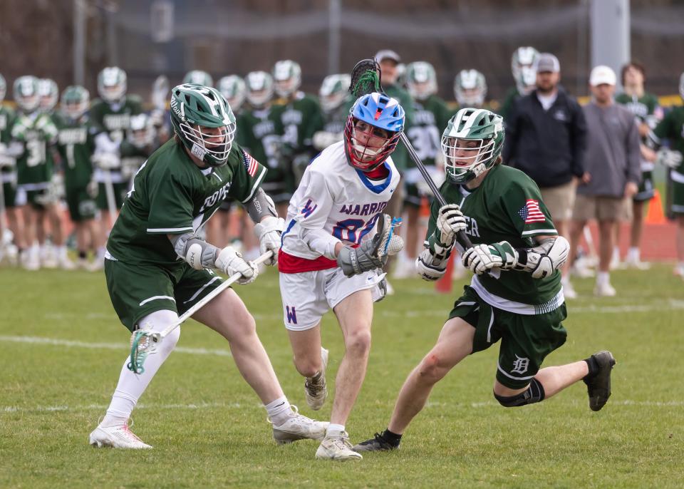 Winnacunnet's Beckett Rath, center, splits Dover defenders Jax Doyle (14) and Riley Joyce (29) in Wednesday's boys lacrosse game in Hampton. Rath had four goals and one assist for Winnacunnet in its 13-4 win.