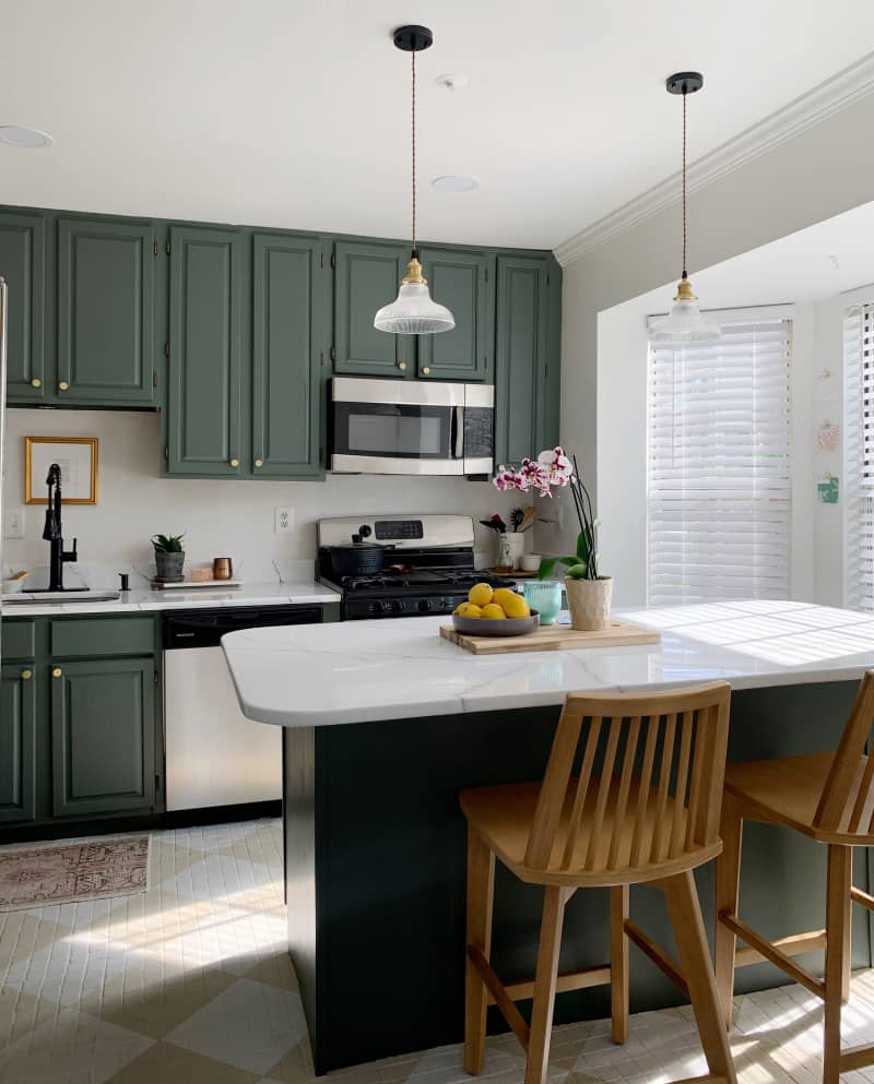 Kitchen with green cabinets and painrws checkerboard floor.