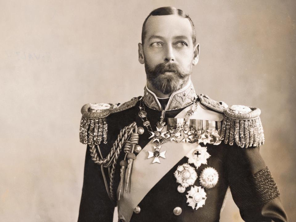 George in an intricate uniform with sashes and medals. He has a handlebar mustache.