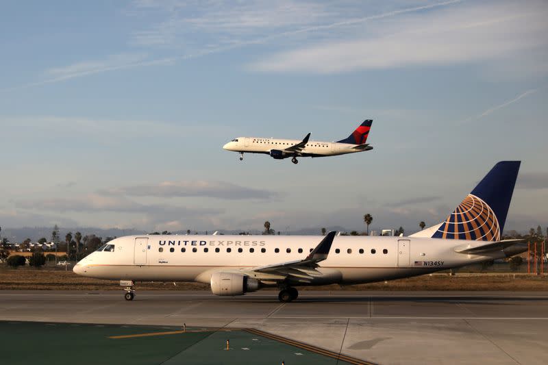 A Delta Connection plane lands as a United Express plane waits to take off at LAX airport in Los Angeles