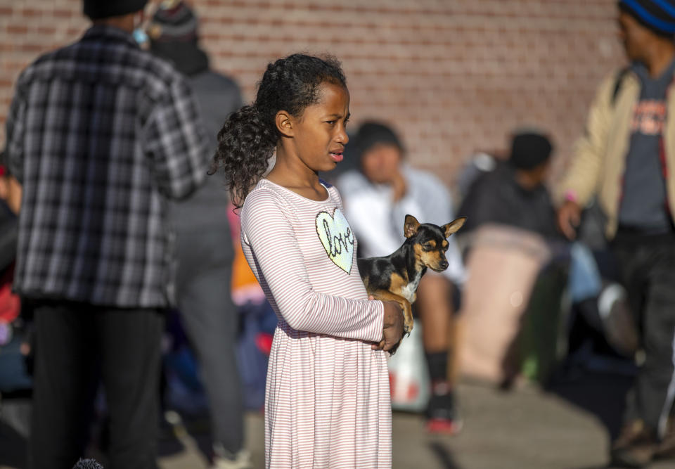 A migrant child holds her dog while camping outside the Sacred Heart Church in downtown El Paso, Texas, Sunday, Jan. 8, 2023. President Joe Biden arrived in Texas on Sunday for his first trip to the U.S.-Mexico border since taking office, stopping in El Paso after two years of hounding by Republicans who have hammered him as soft on border security while the number of migrants crossing spirals. (AP Photo/Andres Leighton)