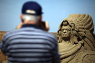 WESTON-SUPER-MARE, ENGLAND - JULY 04: A visitor to Weston-super-Mare's Sand Sculpture Festival stops to take a photograph of some of the sand art on July 4, 2011 in Weston-Super-Mare, England. Now in its fourth year and with a Amazon Jungle theme for 2011, the seaside resort's event attracts top sand sculptors from across the world and runs throughout the summer months. (Photo by Matt Cardy/Getty Images)