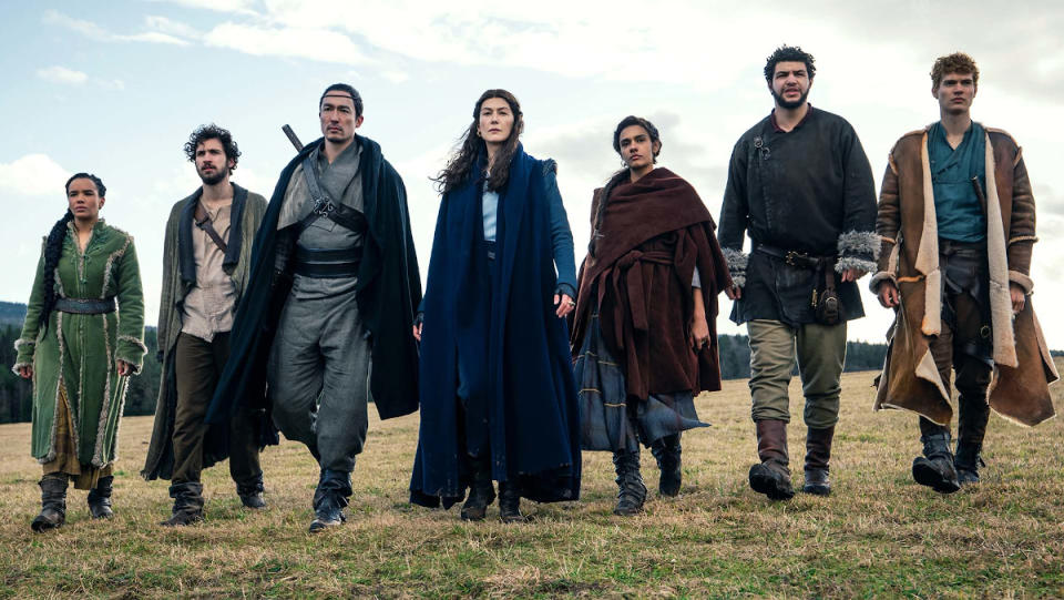 The main cast of The Wheel of Time walk across a field