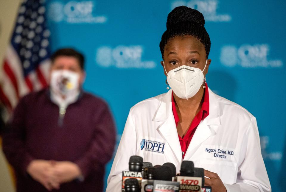 Dr. Ngozi Ezike of the Illinois Department of Public Health answers questions during a press conference Dec. 15 at OSF HealthCare Jump Trading and Simulation Center in Peoria. In the background is Gov. J.B. Pritzker. Five medical workers were inoculated with the first dose of the Pfizer COVID-19 vaccine.