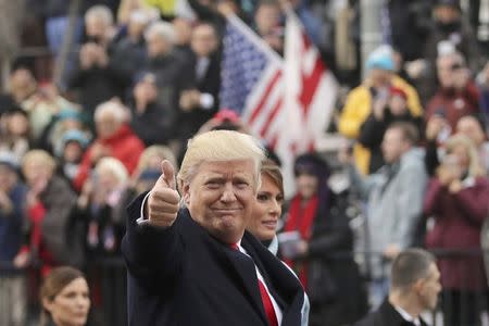 U.S. President Donald Trump points to the stands as he walks with his wife Melania during the Inaugural Parade in Washington, January 20, 2017. REUTERS/Carlos Barria