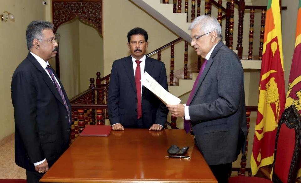 In this photograph provided by the Sri Lankan President's Office, Ranil Wickremesinghe takes oath as the interim President in Colombo, Sri Lanka, Friday, July 15, 2022. Prime Minister Wickremesinghe was sworn in as Sri Lanka's interim president Friday until Parliament elects a successor to Gotabaya Rajapaksa, who resigned after mass protests over the country's economic collapse forced him from office. (Sri Lankan President's Office via AP)