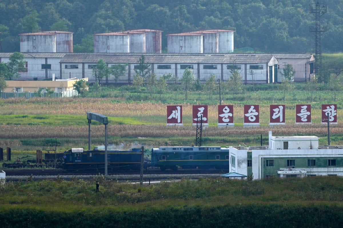 A green train with yellow trimmings, resembling one used by North Korean leader Kim Jong Un on his previous travels, is seen steaming by a slogan which reads ‘Towards a new victory’ on the North Korea border with Russia and China seen from China’s Yiyanwang Three Kingdoms viewing platform in Fangchuan in northeastern China’s Jilin province on Monday, Sept. 11, 2023 (AP)