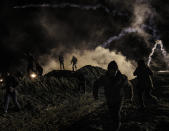 Migrants run as tear gas is thrown by U.S. Border Protection officers to the Mexican side of the border fence after they climbed the fence to get to San Diego, Calif., from Tijuana, Mexico, Tuesday, Jan. 1, 2019. Discouraged by the long wait to apply for asylum through official ports of entry, many migrants from recent caravans are choosing to cross the U.S. border wall and hand themselves in to border patrol agents. (AP Photo/Daniel Ochoa de Olza)