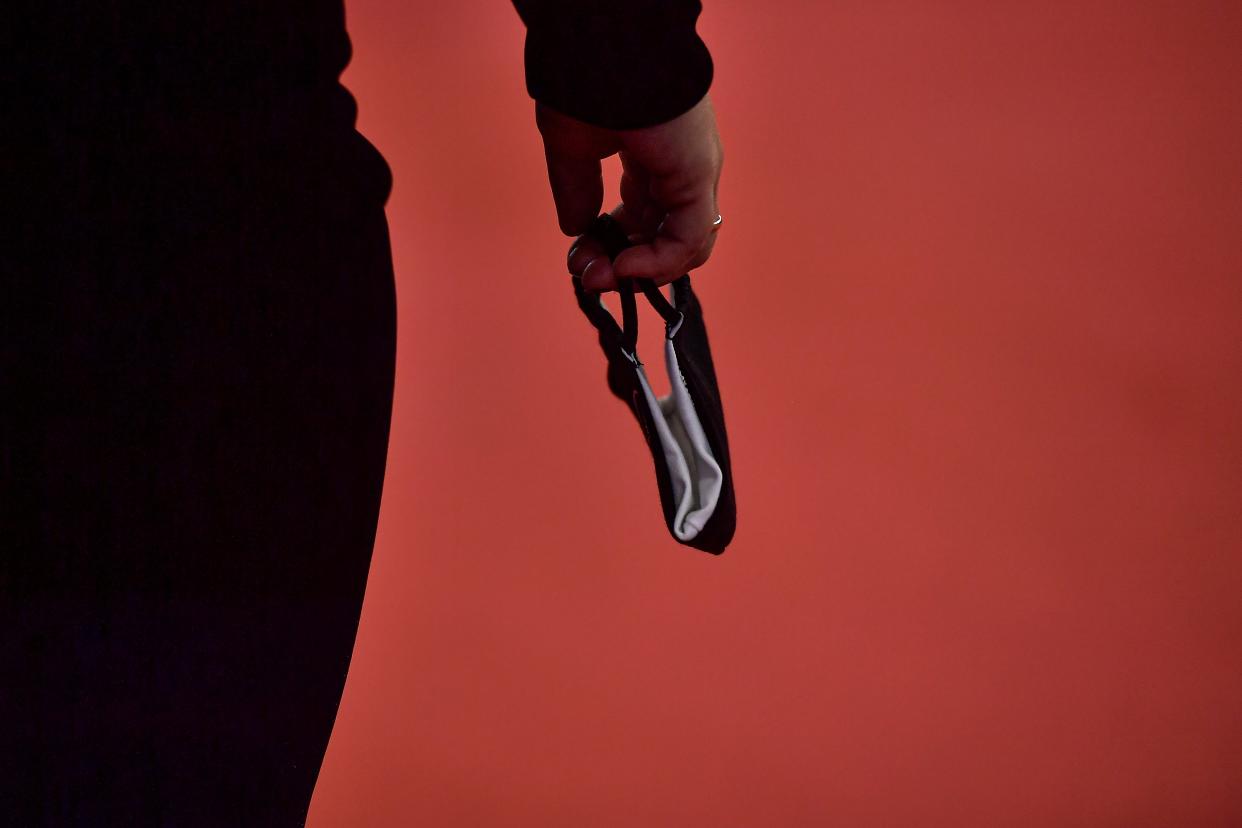 A person holds mask protection to prevent the spread to the coronavirus while walks along red carpet during the opening ceremony at the 68th San Sebastian Film Festival, in San Sebastian, northern Spain, Friday, Sept. 18, 2020. (AP Photo/Alvaro Barrientos) (AP)